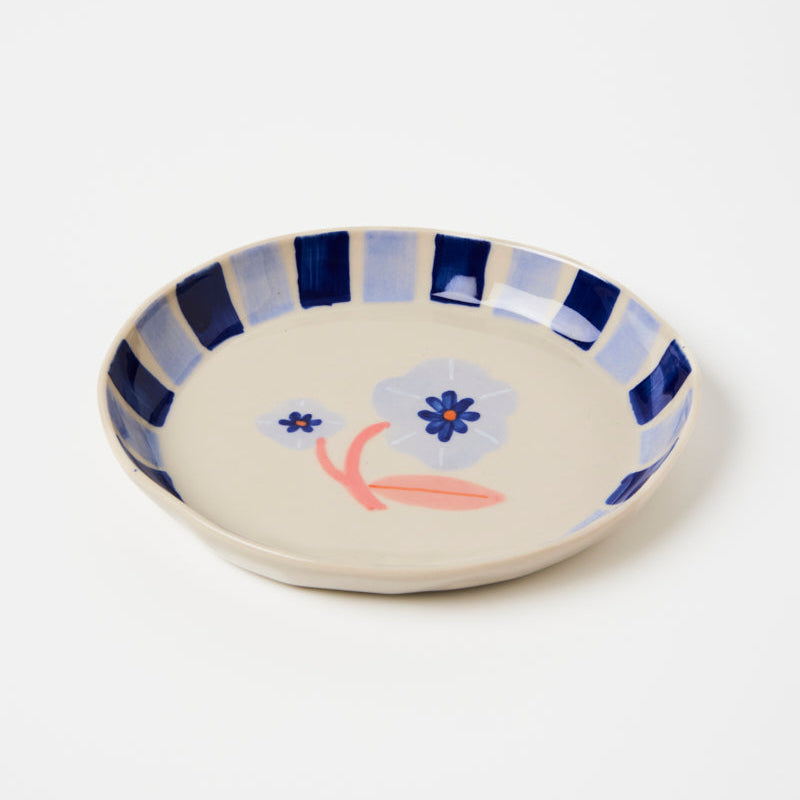 Ceramic plate with floral design and blue stripes on a white background