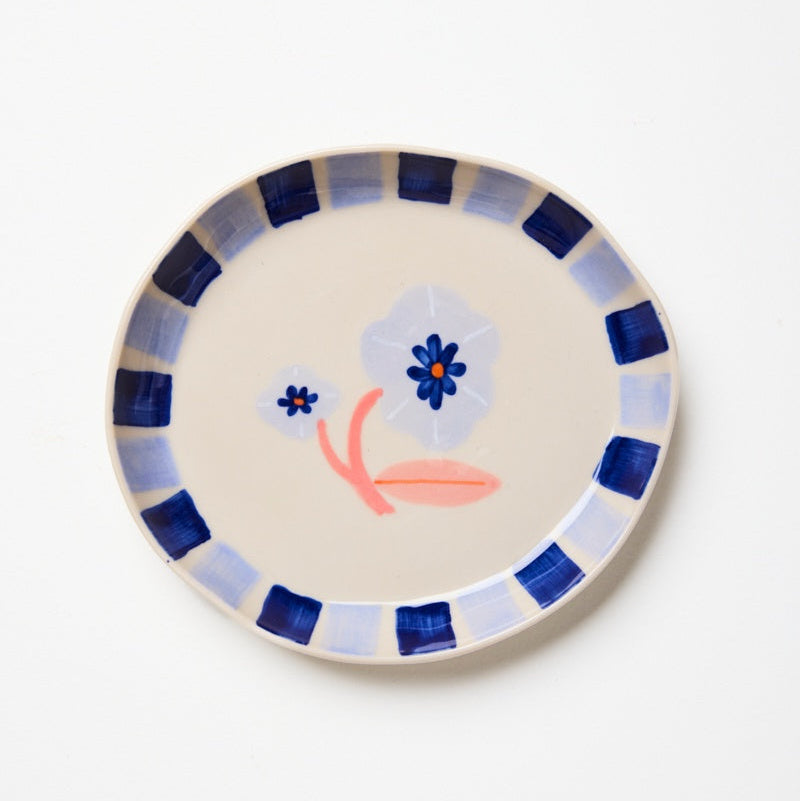 Ceramic plate with floral design and blue striped rim on a white background
