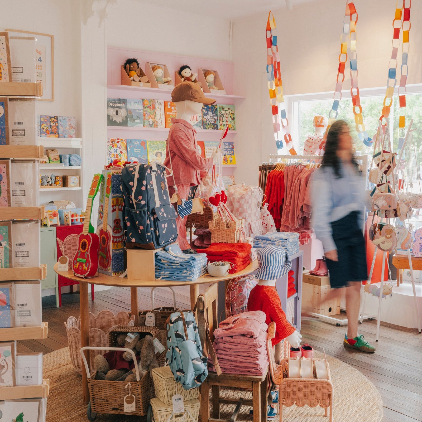 Children's clothing store with shelves and display tables filled with children's clothes and toys.