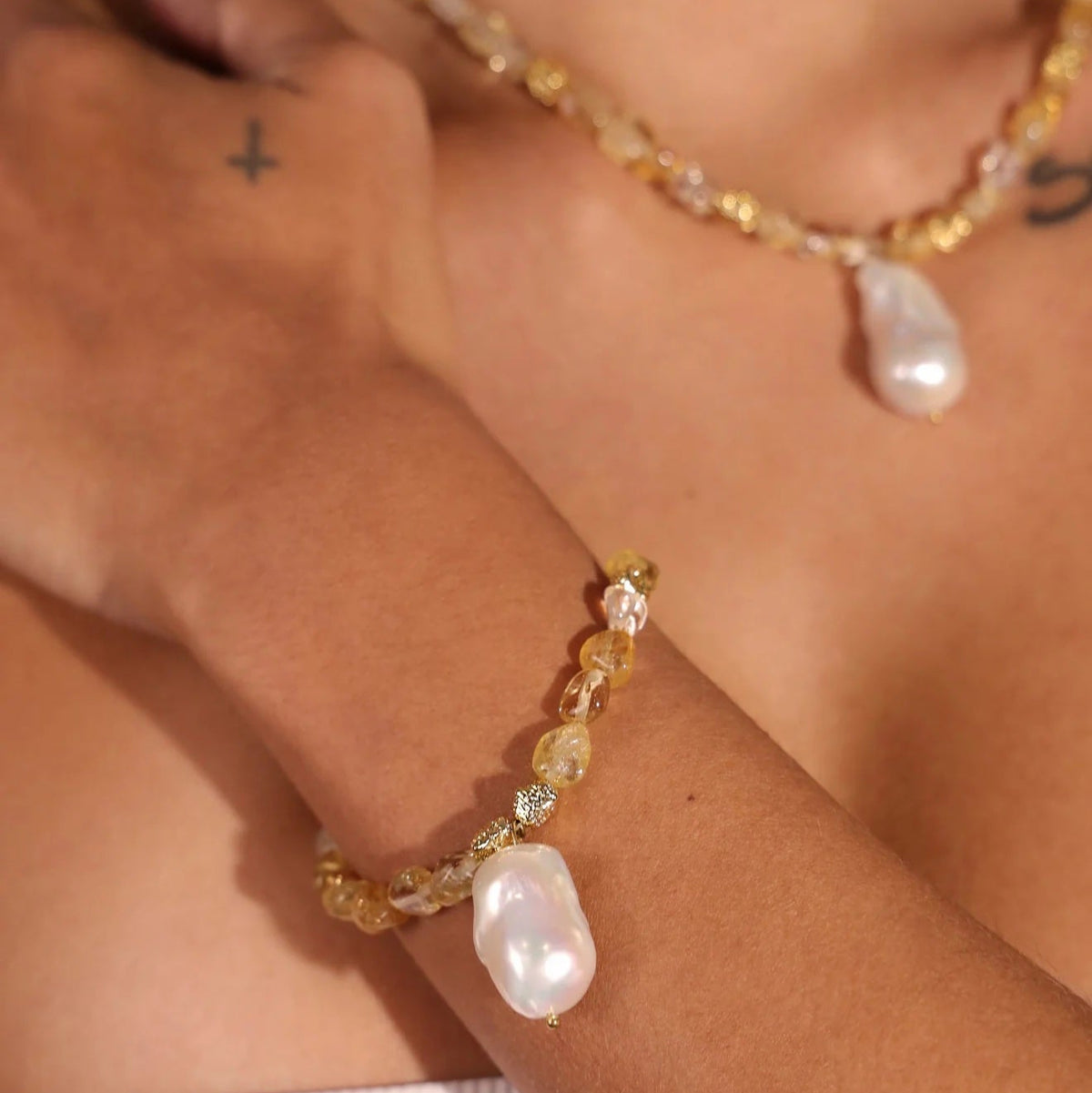 Close-up of a person wearing a beaded bracelet and necklace with large beads on a neutral background